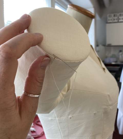 Vaatetuen hihaosa lähikuvassa ja kauempana torso.