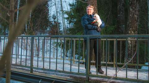 Marjaana Siivola on the bridge with a white wool dog on her lap.