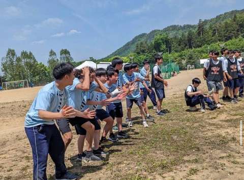 Opiskelijat pelikentällä rivissä