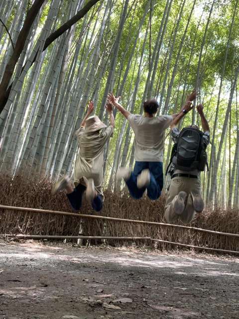 Kolme ihmistä hypänneinä ilmaan metsässä.