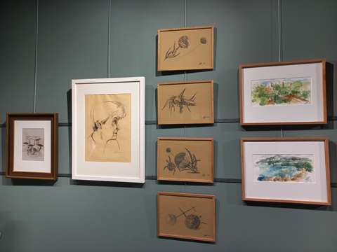 Harmaaksi maalattu seinä, jolle on ripustettu eri kokoisia tauluja. Taulujen takana näkyvät seinään kiinnitetyt magneettijuovat.