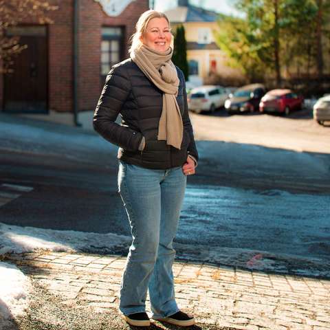 Ninna Suominen is lookin towards camera smiling.