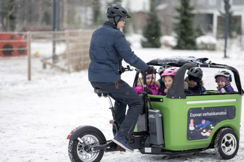  Barnen sitter med hjälmar på sig i Knattebussen medan en vuxen kör.