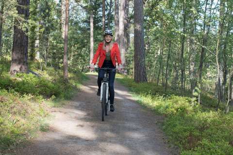 A person riding a gravel road in a forest.
