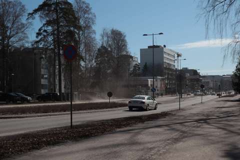 En bil kör på gatan och det virvlar upp damm.
