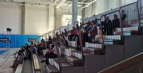 Ihmisiä liikuntahallin katsomossa seuraamassa ohjelmaa.