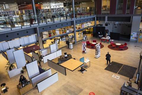 The lobby of the Sello library, pictured from the upper floor, with a group of sofas, bookshelves and customers.
