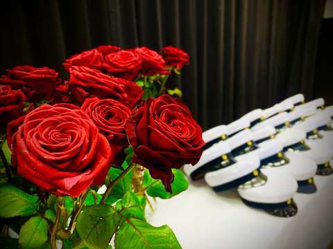 Lähikuva ruusukimpusta ja taustalla ylioppilaslakkeja.