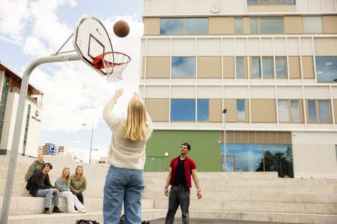 opiskelijat ulkona koulun vieressä koripallokentällä.