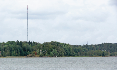 Meren rannalla on paljon puita. Puiden lomasta pilkistää muutama talo.