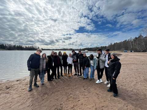 15 nuorta seisoo hiekkarannalla merellä