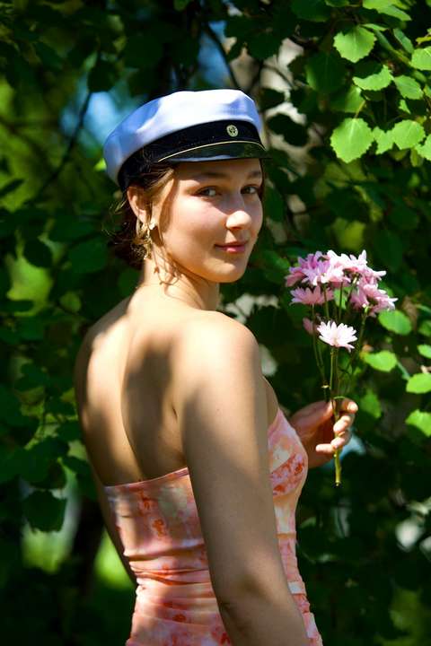 Joanna Räikkönen seisoo puoliksi selin kameraan ylioppilaslakki päässä