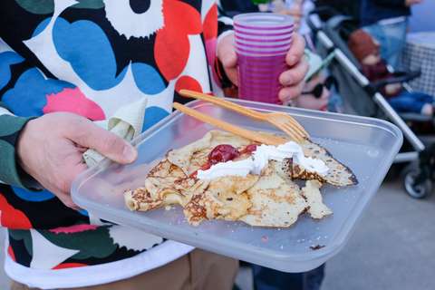 A person wearing a colourful shirt holds a translucent, square plate in one hand and a colourful cup in the other.