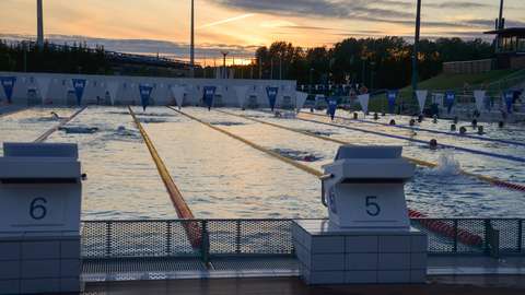 The picture shows the big swimming pool at the Leppävaara outdoor swimming pool. There is a sunset in the background.