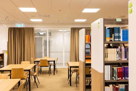 kirjasto, jossa hyllyjä ja pöytiä