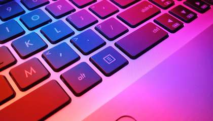 Tietokoneen näppäimistö vaaleanpunaisessa valaistuksessa.