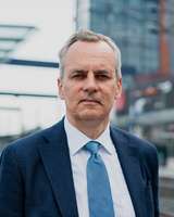 Pukuun pukeutunut mies katsoo kameraan.