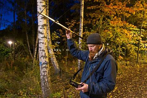 Henkilö pitelee antennia ja katsoo radiovastaanottimen ruutua.
