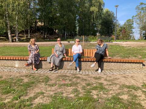 Fyra personer sitter på en lång bänk.