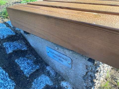 I ändan på bänken finns en skylt med texten ”Kaupungintalo 1971–2022”.