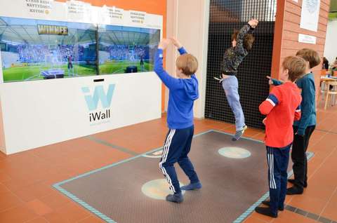 Lapsia pelaamassa liikuntapeliseinällä liikuntapeliä.