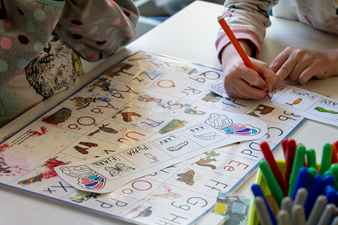Förskolebarn sitter vid ett bord och gör uppgifter.