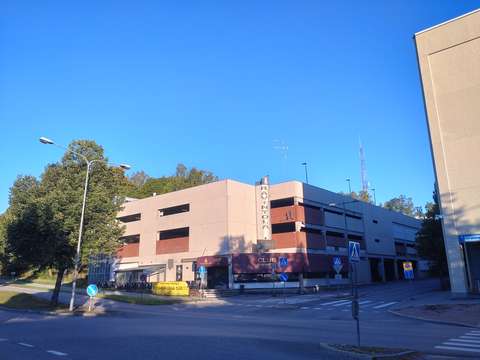 Näkymä kaava-alueesta nykytilanteessa Kirkkojärventien suunnalta katsottuna. Etualalla näkyy Kirkkojärventien ja Kannusillankadun risteys. Sen takana on alueella sijaitseva oleva pysäköintilaitos, jonka päädyssä sijaitsee ravintola. 