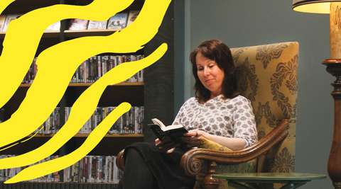 A person reading a book is sitting in an armchair.