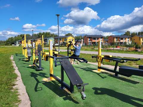 Kuvassa näkyy ulkokuntosali ja yhdessä laitteessa on mies treenaamassa.