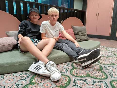 Varhaisnuoret pojat Milo ja Oliver istumassa kirjaston tyynyillä lattian tuntumassa.