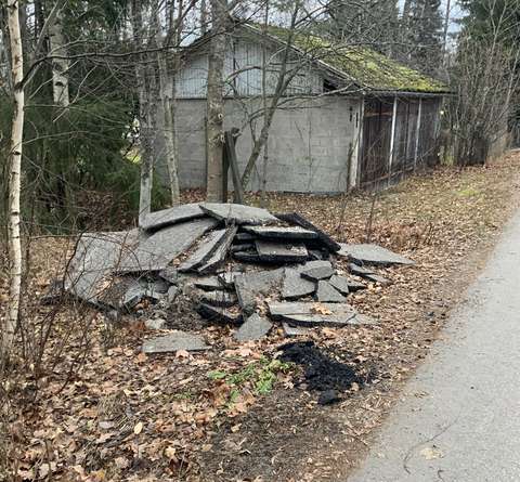 Den gamla byggnaden och en hög med riven asfalt vid vägkanten.