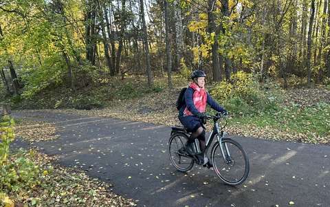 En person med cykelhjälm cyklar i ett höstligt landskap.