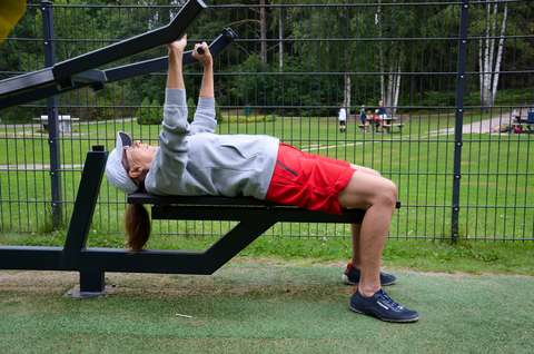 Kuvassa nainen on ulkokuntosalilla pystypunnerruslaitteessa.