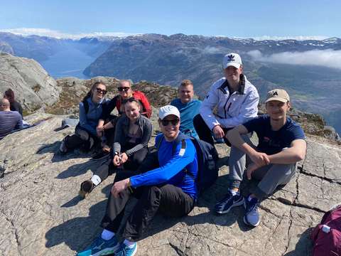 opiskelioita istumassa, taustalla norjalainen vuorimaisema