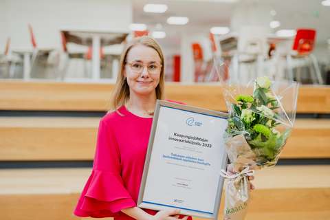 Henkilö kädessään kukkakimppu ja kehystetty taulu, jossa lukee kaupunginjohtajan innovaatiopalkinto.
