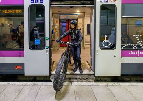Pyöräilijä astuu ulos junasta.