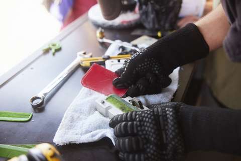 Hands covered by protective gloves are removing a plastic comb from an aluminium mould.