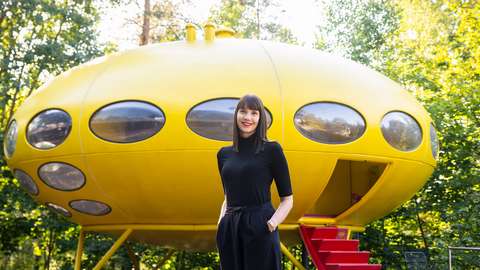 Henkilö seisoo keltaisen rakennuksen edessä.