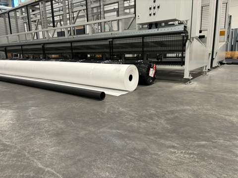 På golvet i en stor hall finns ett svart plaströr och en stor vit tygrulle.