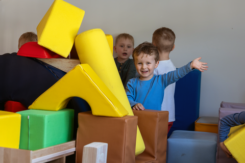 Lapset rakentavat värikkäistä isoista rakennuspalikoista majaa.