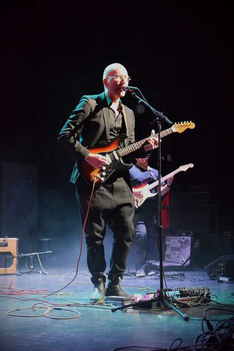 Mies soittaa sähkökitaraa lavalla.