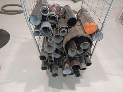 Svarta plaströr av olika storlek i en rullcontainer.