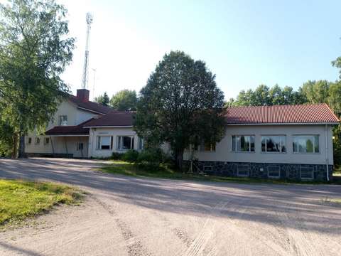 Matala vaalea rakennus, jossa on punainen katto. Edessä hiekkakenttää.