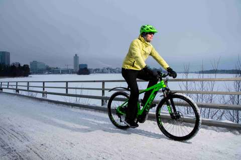 A wintry seashore. A person is riding a bicycle on a bicycle lane cleared of snow.