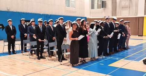 ylioppilaita juhlasalissa lakit päässä.