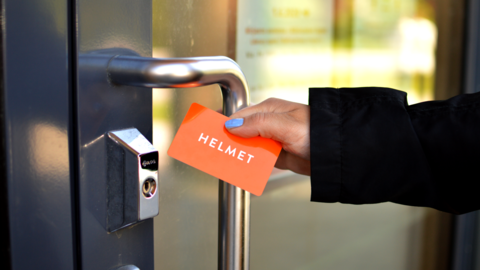 A hand holding a library card opens a door.