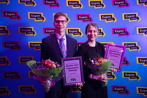 Kuvassa on nuori mies ja nainen, joilla on käsissään palkintotaulut ja kukkakimput.