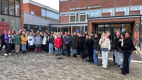 osallistujat seisovat yhteiskuvassa rakennuksen edessä