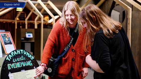 Niina Bruun and a customer are looking at an event poster.