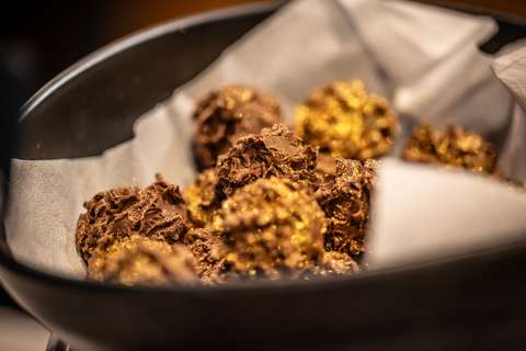 Kultakuorrutetut samppanjatryffelit tarjolla mustassa astiassa.